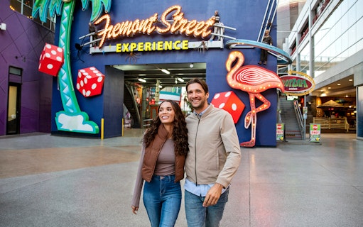 Couple walking at Fremont Street Experience, Las Vegas, with neon signs and dice.