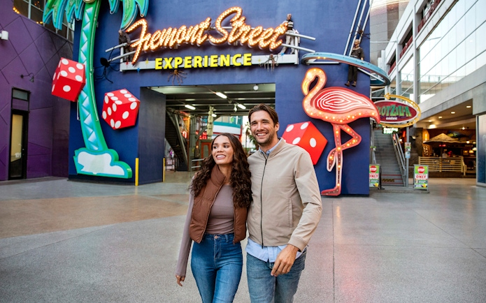Couple walking at Fremont Street Experience, Las Vegas, with neon signs and dice.
