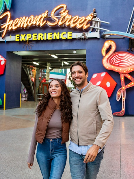 Couple walking at Fremont Street Experience, Las Vegas, with neon signs and dice.