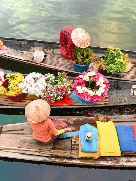 Local vendors selling colorful flowers on boats in Amphawa floating market, Thailand.