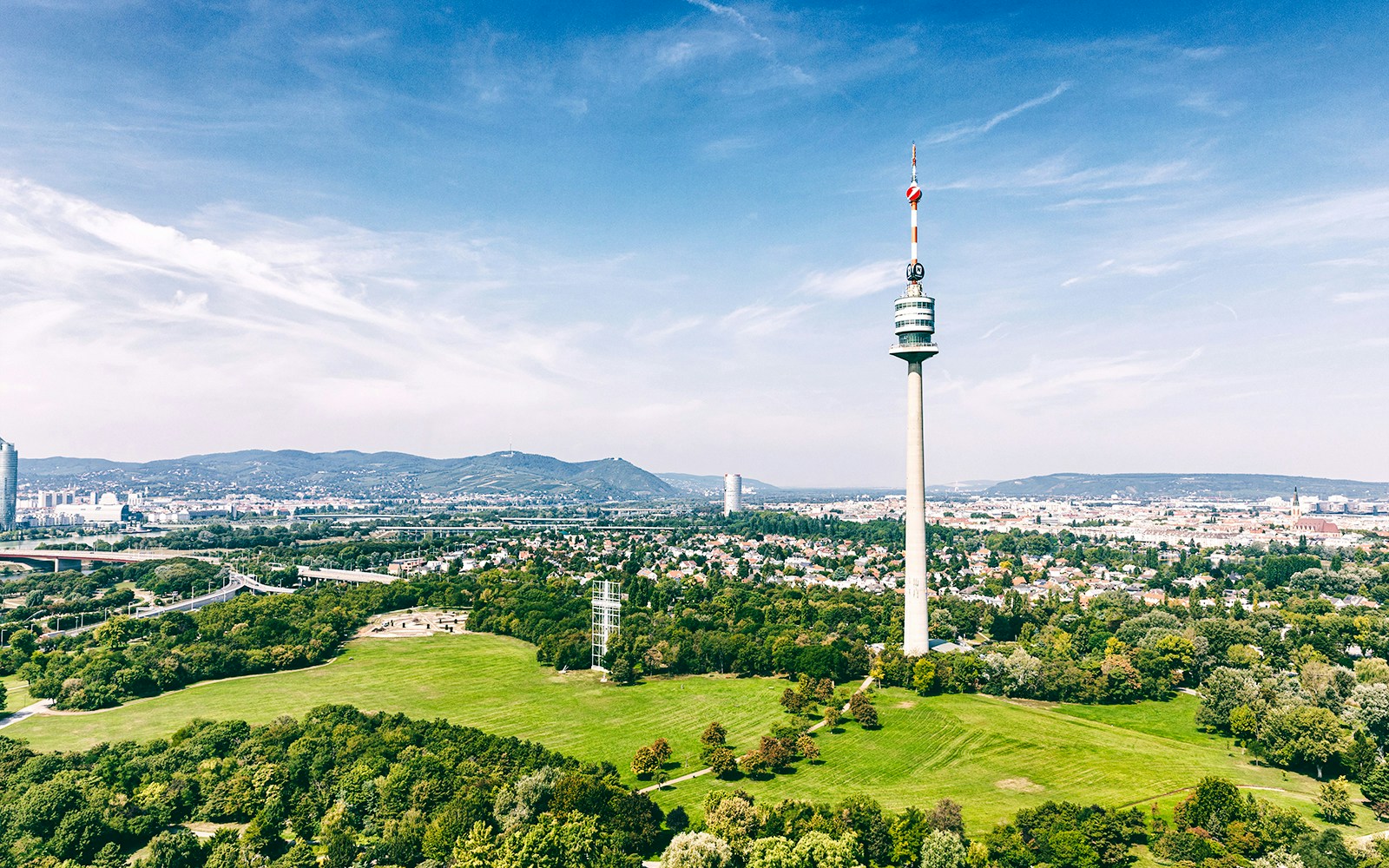 Danube Tower overlooking Vienna cityscape and green parkland.
