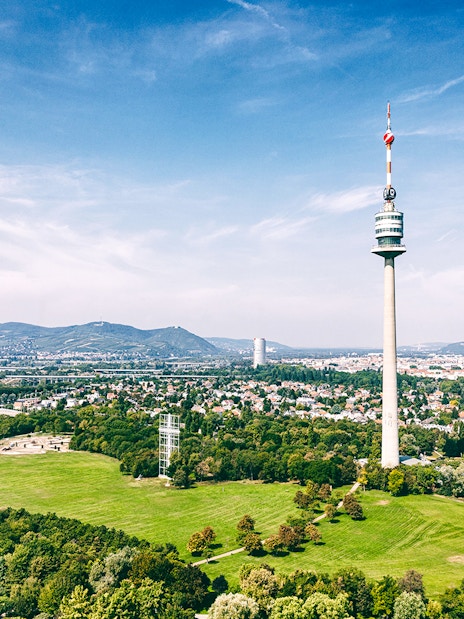 Danube Tower overlooking Vienna cityscape and green parkland.