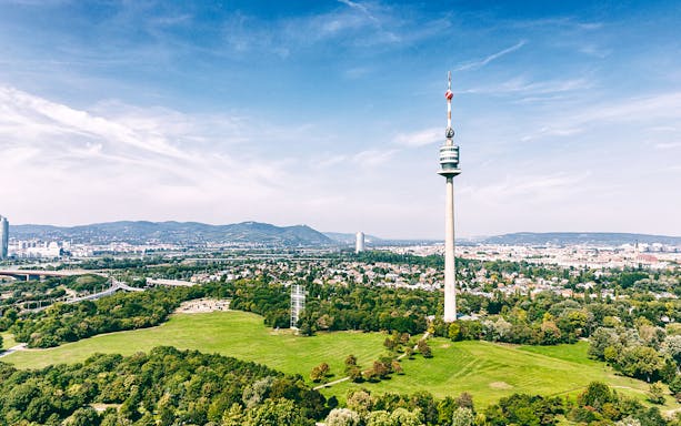 Danube Tower overlooking Vienna cityscape and green parkland.