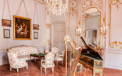 Elegant room with ornate decor, harp, and piano at Caumont Centre d’Art, Aix-en-Provence.