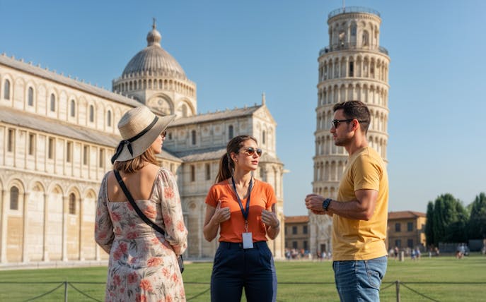 Guide talking to a couple in front of Pisa Cathedral and Leaning Tower, Italy.