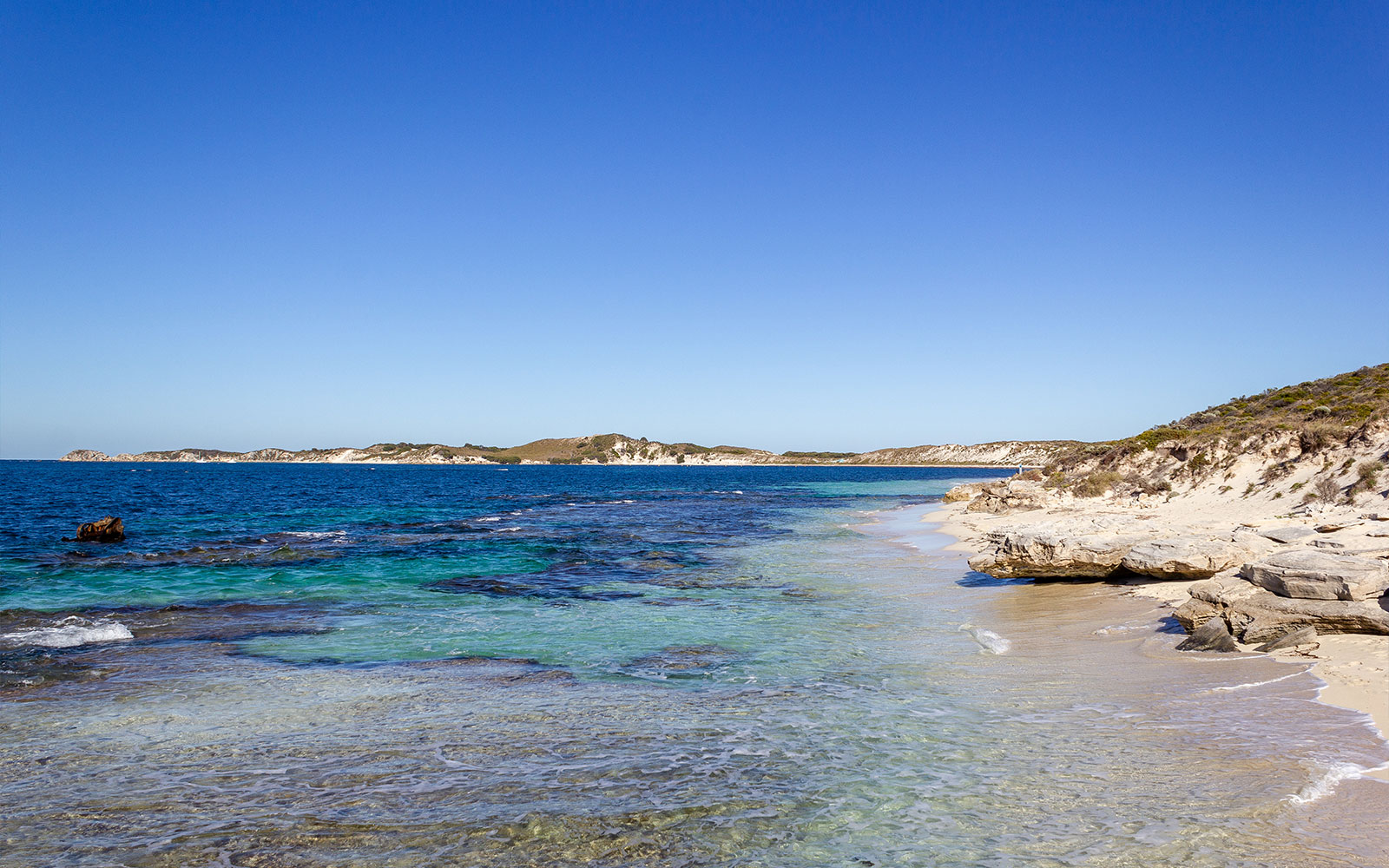 Coastal view of Rottnest Island, Australia, with clear blue water and sandy beach.