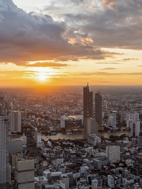 Aerial view of Bangkok skyline from Mahanakhon SkyWalk at sunset.