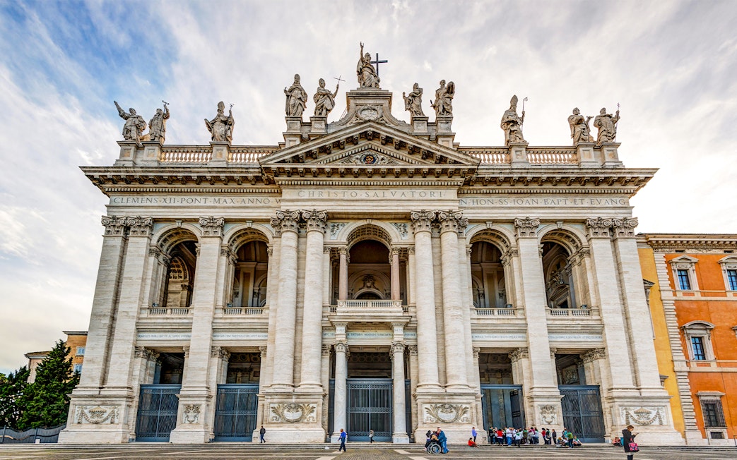 St. John Lateran Basilica facade in Rome with visitors outside.