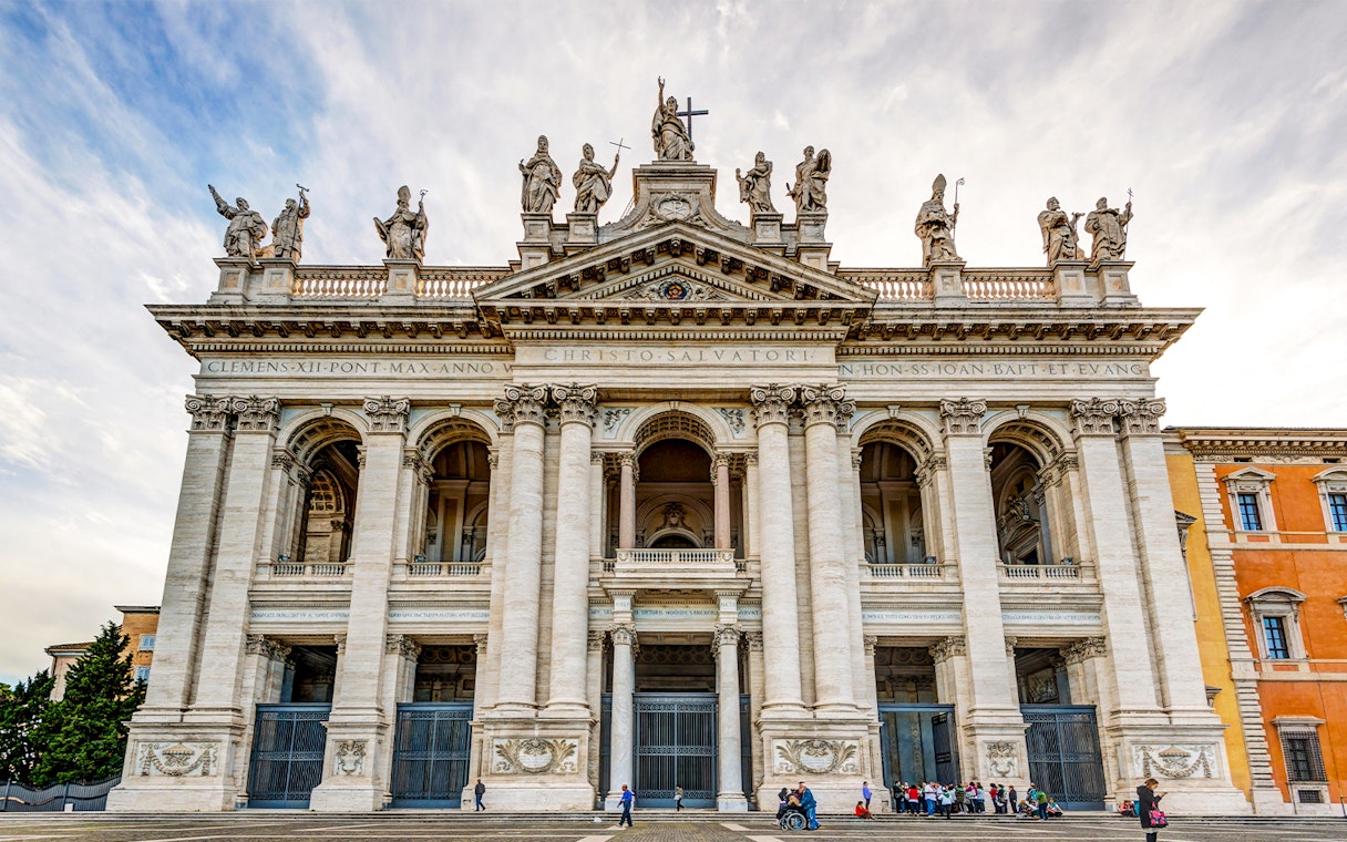 St. John Lateran Basilica facade in Rome with visitors outside.