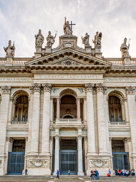 St. John Lateran Basilica facade in Rome with visitors outside.