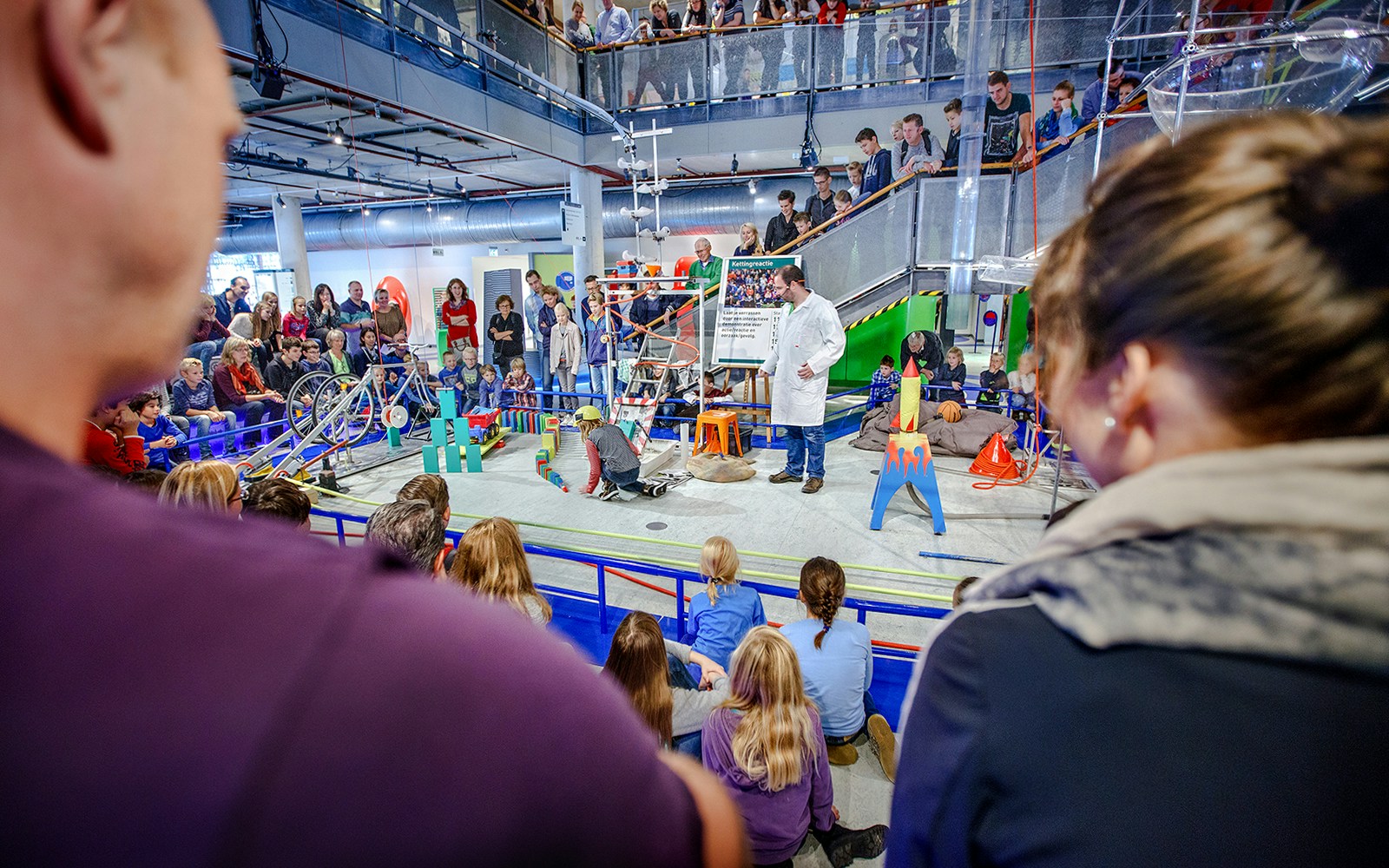 Parents observing children engaging with interactive exhibits at NEMO Science Museum, Amsterdam.