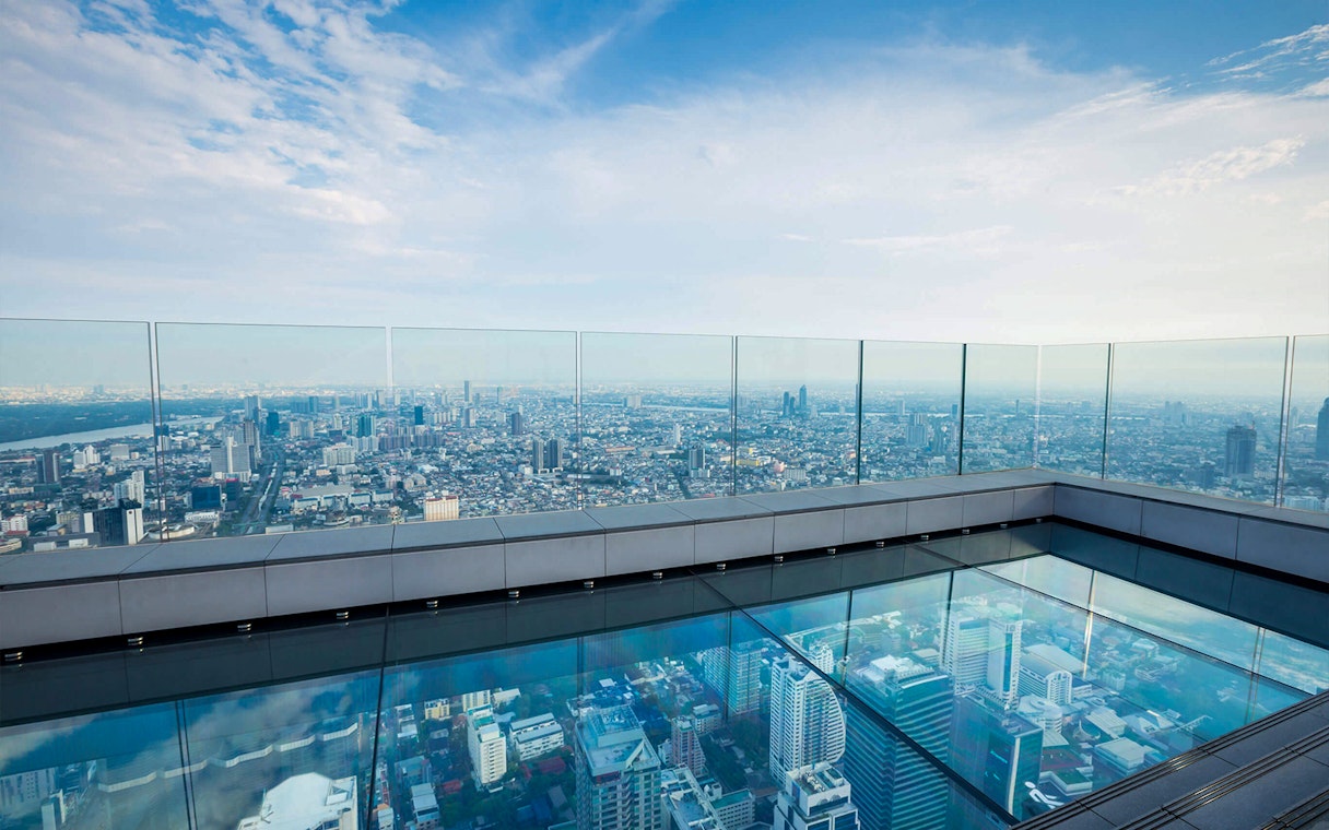 Mahanakhon SkyWalk glass floor with panoramic view of Bangkok cityscape.