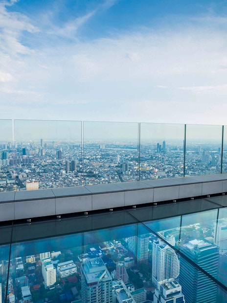 Mahanakhon SkyWalk glass floor with panoramic view of Bangkok cityscape.