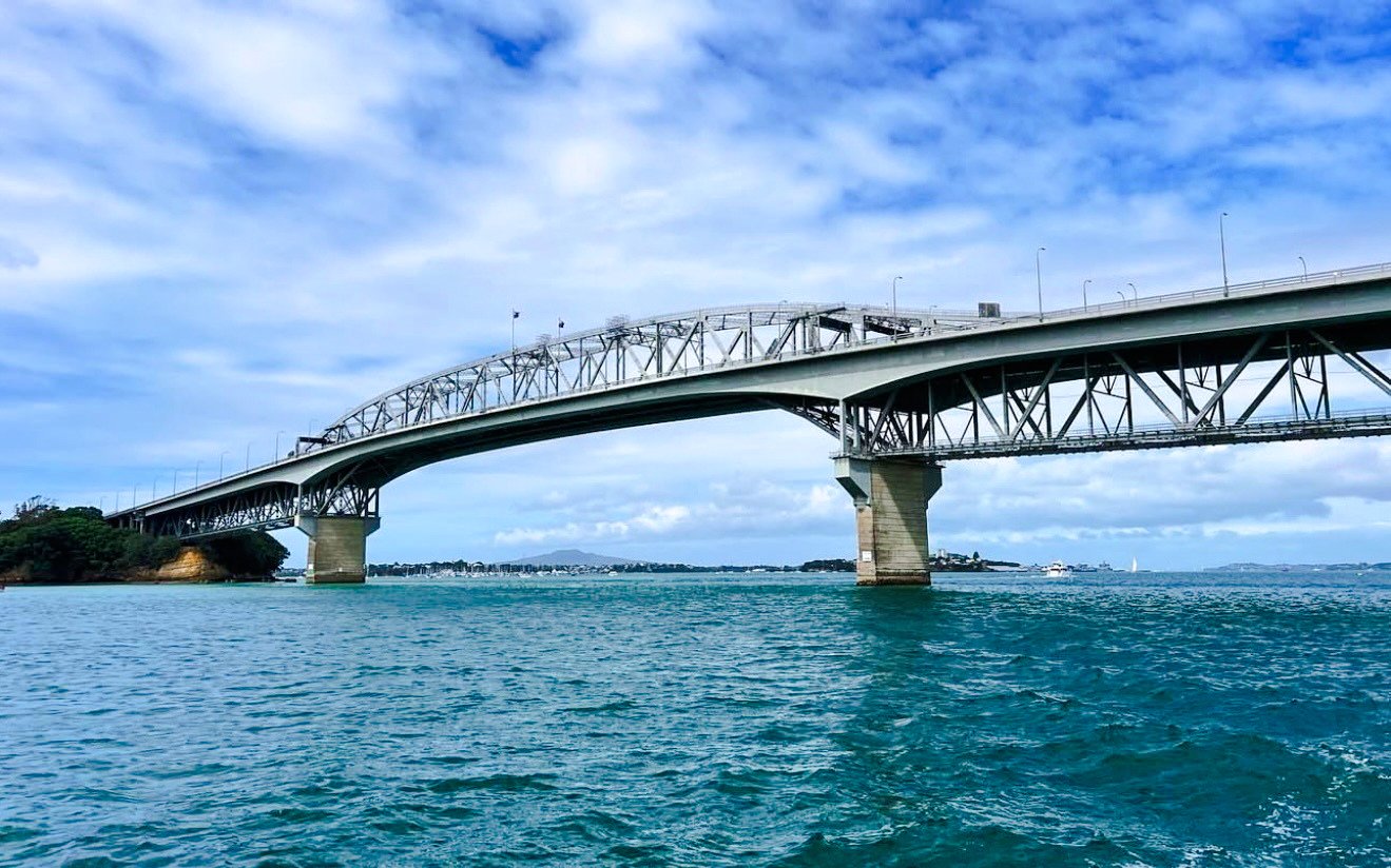 Auckland Harbour Bridge over blue water during scenic cruise.
