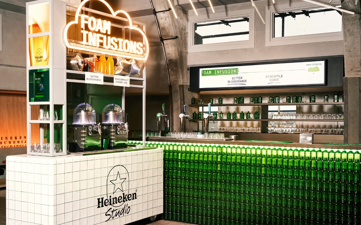 Heineken Experience interior with Foam Infusions bar and green bottle display.