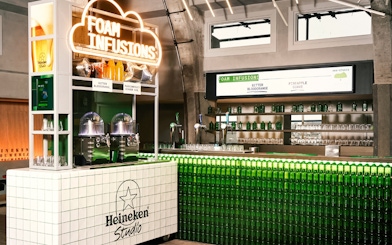 Heineken Experience interior with Foam Infusions bar and green bottle display.