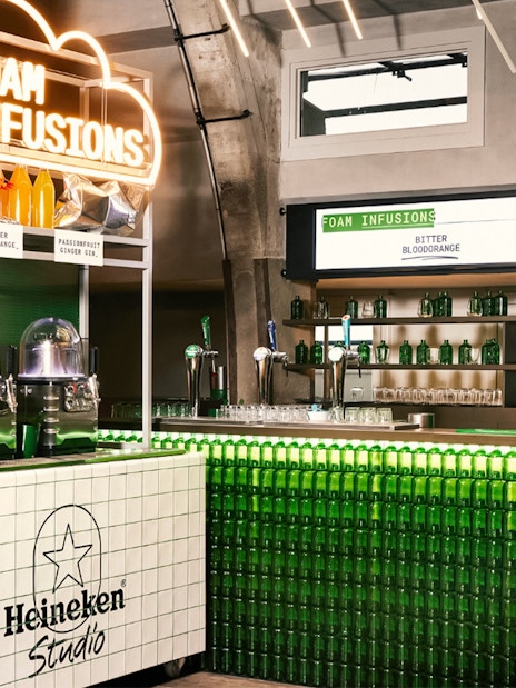 Heineken Experience interior with Foam Infusions bar and green bottle display.