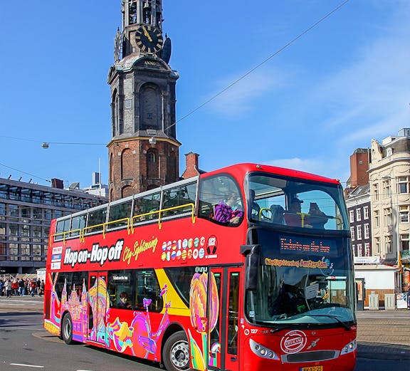 Hop-on hop-off bus in front of Munttoren tower, Amsterdam city sightseeing.