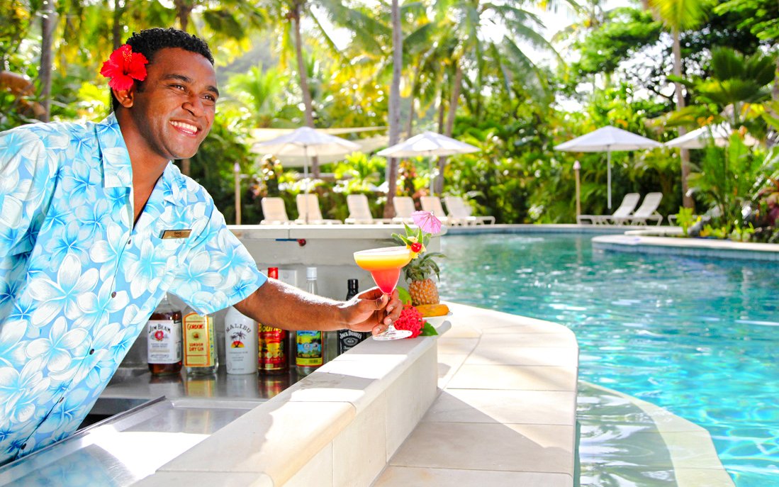 Staff member offering a cocktail by the pool, Castaway Island, Fiji.