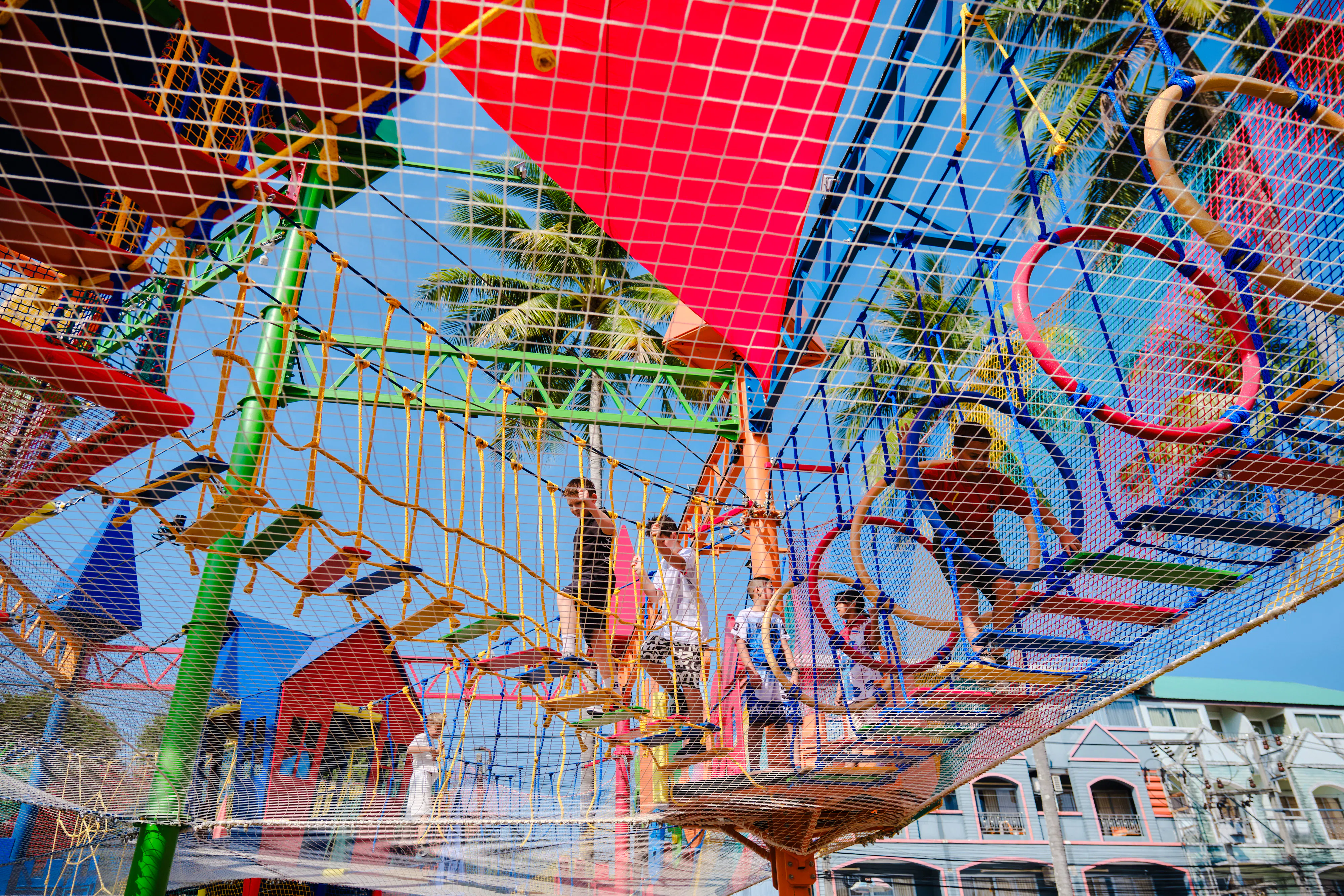 Children navigating colorful ropes course at outdoor adventure park, Phuket.