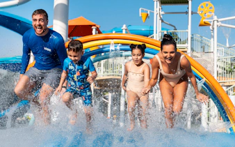 Family enjoying rainbow water arches at Grand Hyatt waterpark, Dubai.