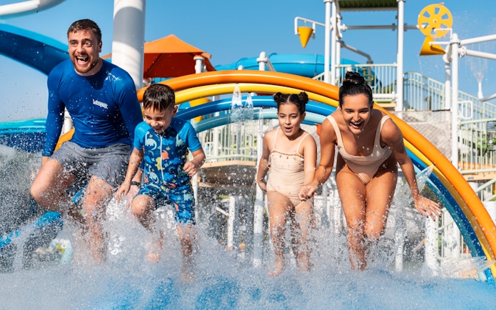 Family enjoying rainbow water arches at Grand Hyatt waterpark, Dubai.