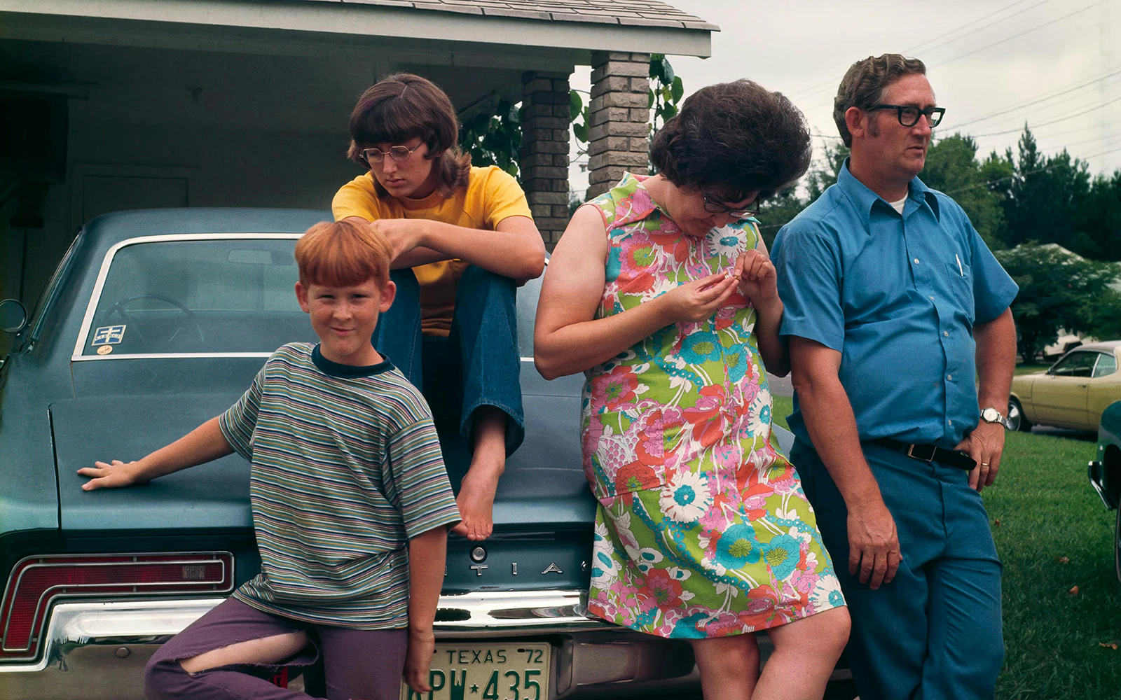 Family posing by a vintage car at The Anonymous Project: No Place Like Home Exhibit, Fotografiska Berlin.