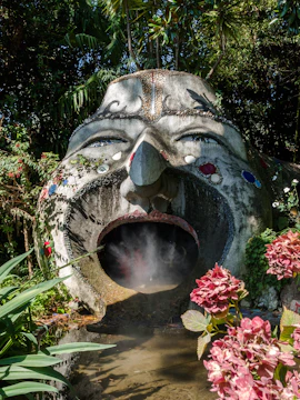 Sculpture with open mouth and steam in ANIMA Garden, Marrakech, surrounded by lush plants.