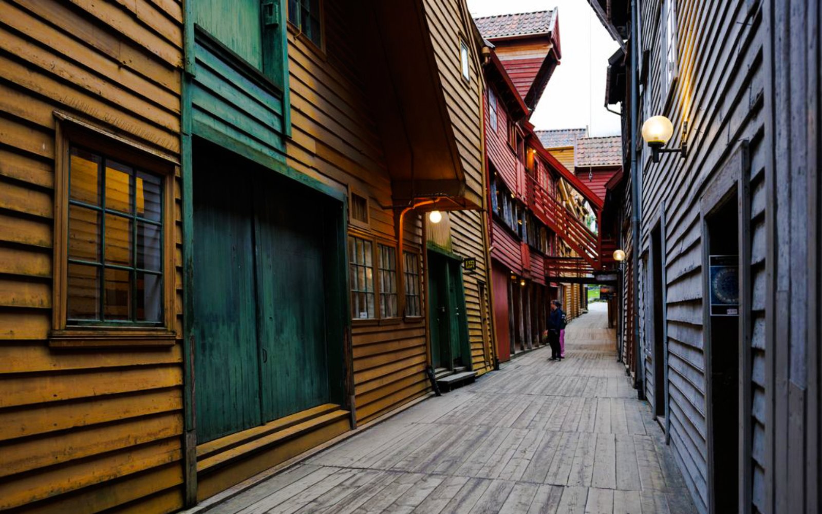Guests walking through historic wooden alley in Bryggen, Bergen, Norway.