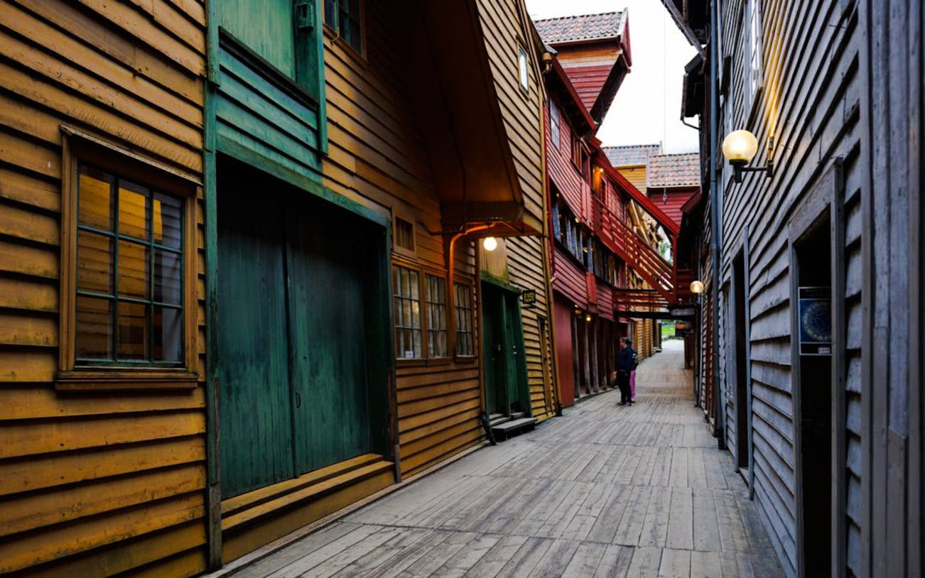 Guests walking through historic wooden alley in Bryggen, Bergen, Norway.