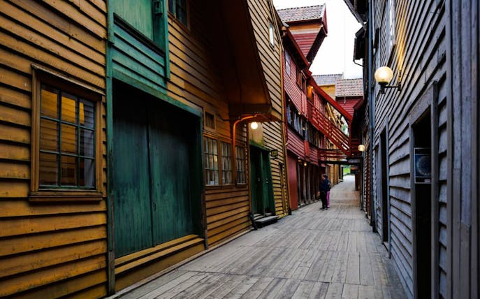 Guests walking through historic wooden alley in Bryggen, Bergen, Norway.