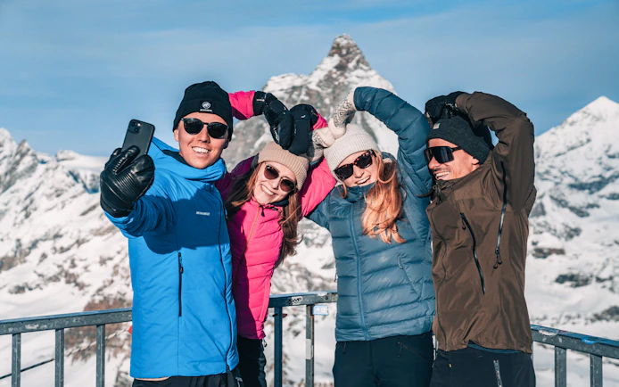 Group taking a selfie on a snowy mountain viewing platform.