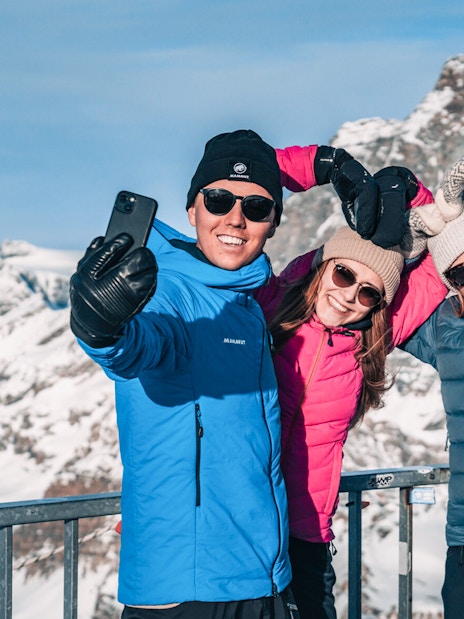 Group taking a selfie on a snowy mountain viewing platform.