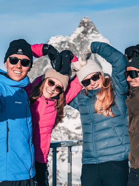 Group taking a selfie on a snowy mountain viewing platform.