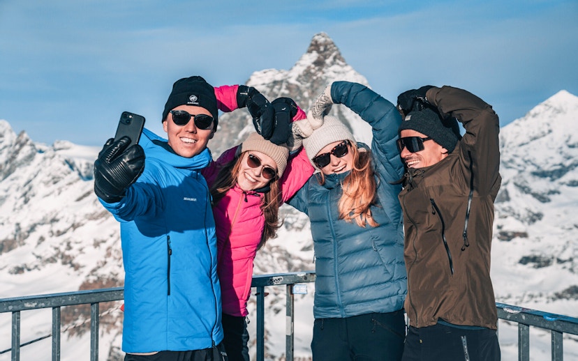 Group taking a selfie on a snowy mountain viewing platform.