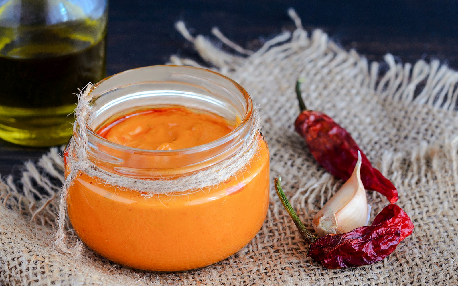 Jar of Canarian mojo sauce with garlic and dried peppers on burlap.