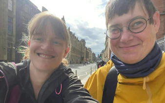 Two people smiling on a street in Glasgow during a self-guided city exploration game.