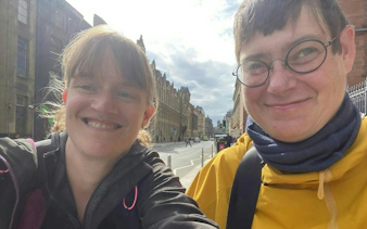 Two people smiling on a street in Glasgow during a self-guided city exploration game.