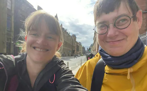 Two people smiling on a street in Glasgow during a self-guided city exploration game.