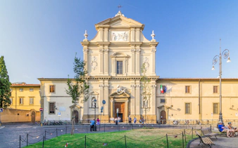 Facade of San Marco Church in Florence, Italy, with visitors and surrounding plaza.