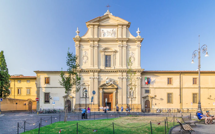 Facade of San Marco Church in Florence, Italy, with visitors and surrounding plaza.