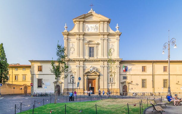 Facade of San Marco Church in Florence, Italy, with visitors and surrounding plaza.
