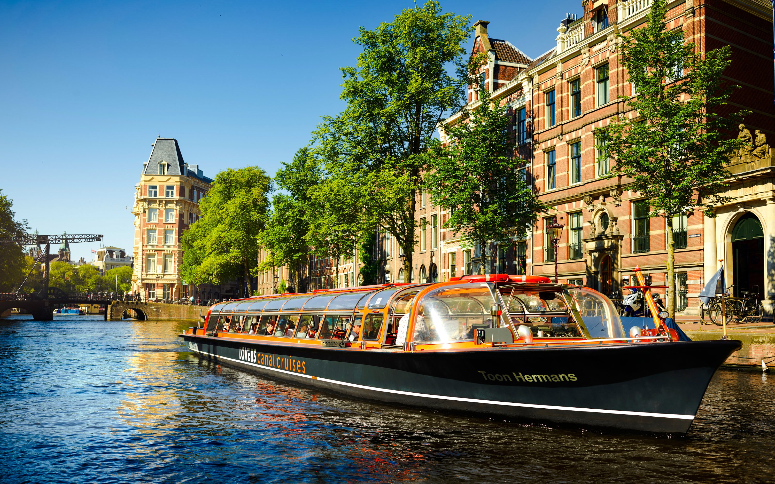 Lovers Canal Cruise boat on Amsterdam canal with historic buildings in the background.