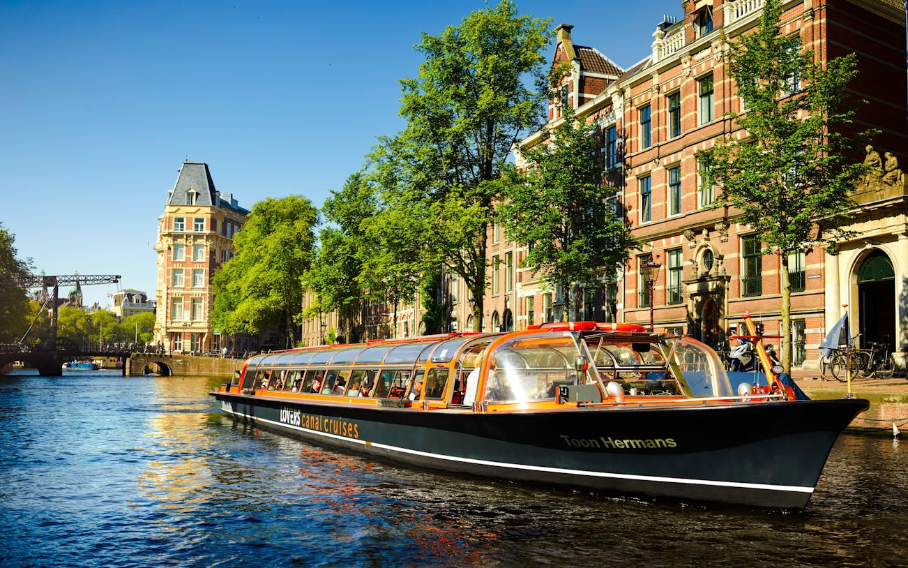 Lovers Canal Cruise boat on Amsterdam canal with historic buildings in the background.
