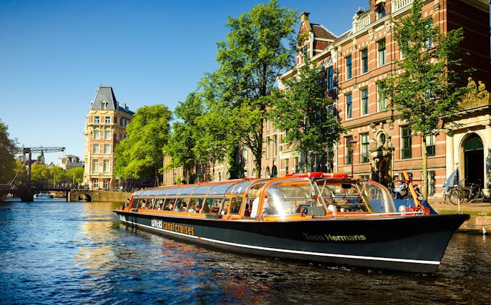 Lovers Canal Cruise boat on Amsterdam canal with historic buildings in the background.