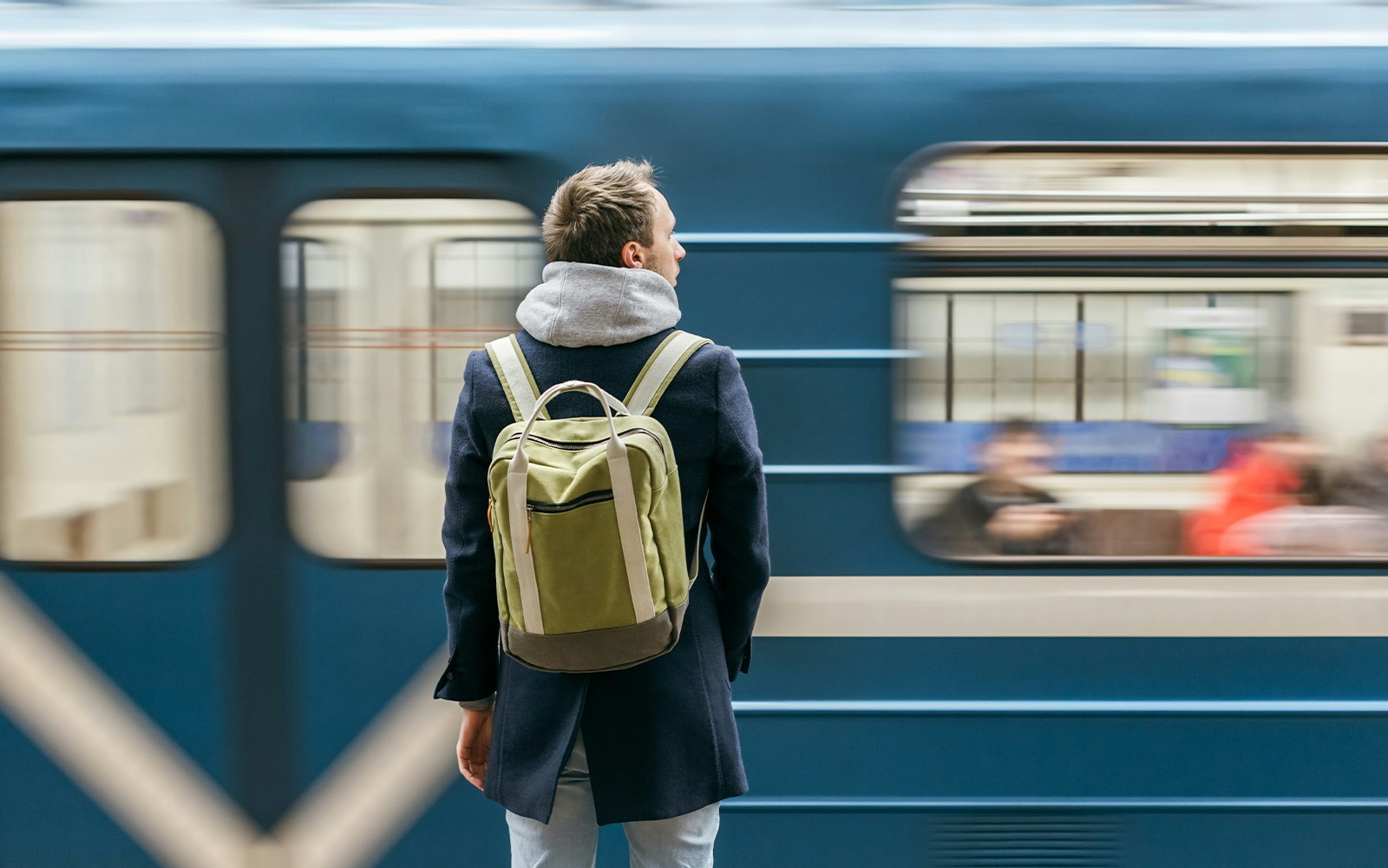 Man waiting at a train station platform in a European city.