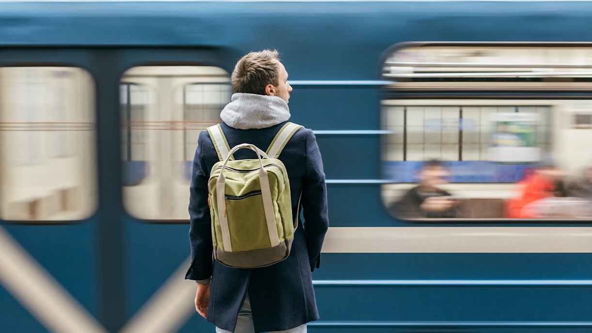 Man waiting at a train station platform in a European city.