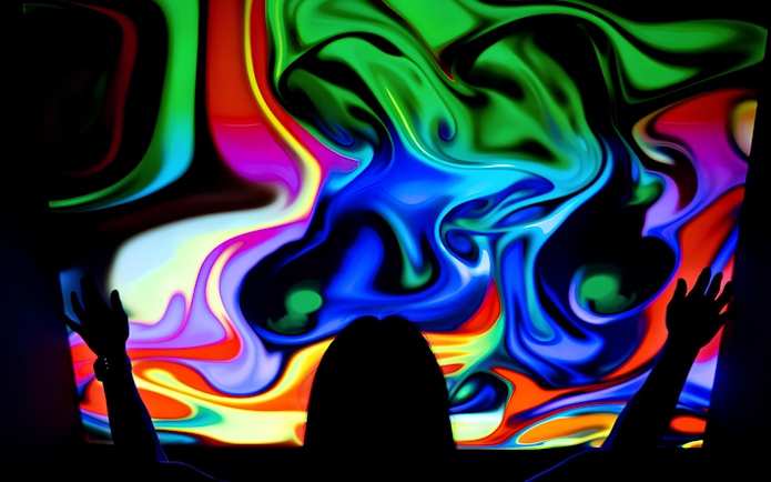 Visitor interacting with colorful digital display at DeJa Vu Museum exhibit.
