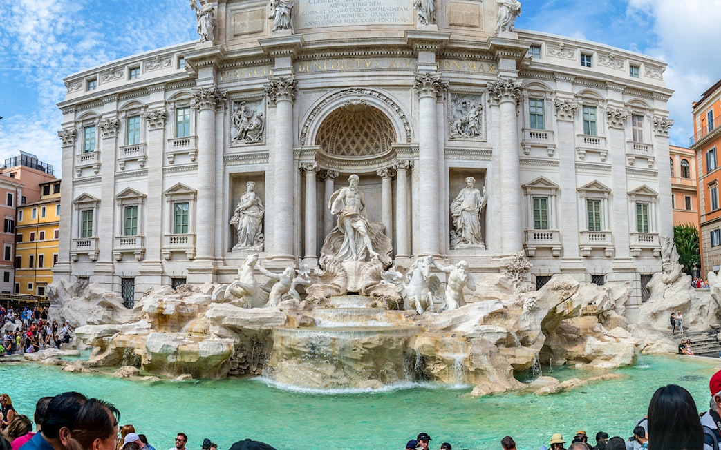 Trevi Fountain with sculptures and tourists in Rome, Italy.