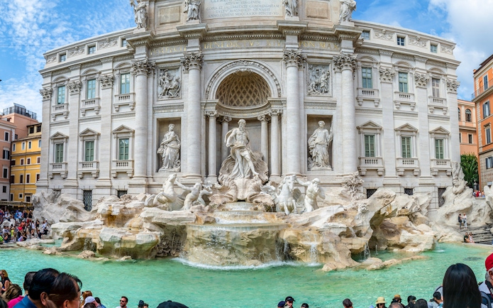Trevi Fountain with sculptures and tourists in Rome, Italy.